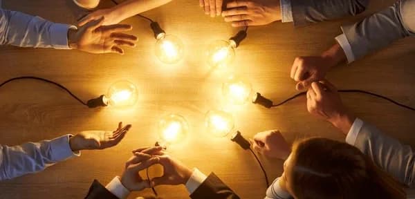 Team gathered around light bulbs representing shared ideas and innovation